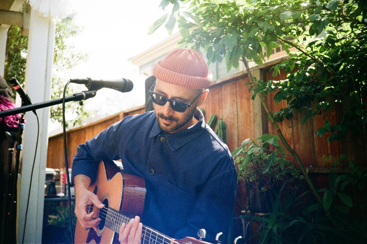 Jaime Tjahaja playing acoustic guitar at a backyard show